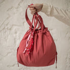 Sac bourse Manhattan rouge corail taille M tenu à la main – patron de couture Ikatee