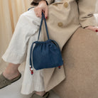 Sac bourse Manhattan en denim bleu taille S tenu à la main – patron de couture Ikatee